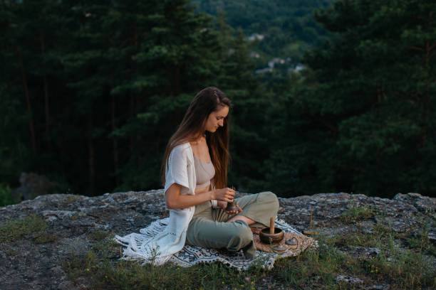 Woman meditating outdoors on a rock, practicing emotional wound release.
